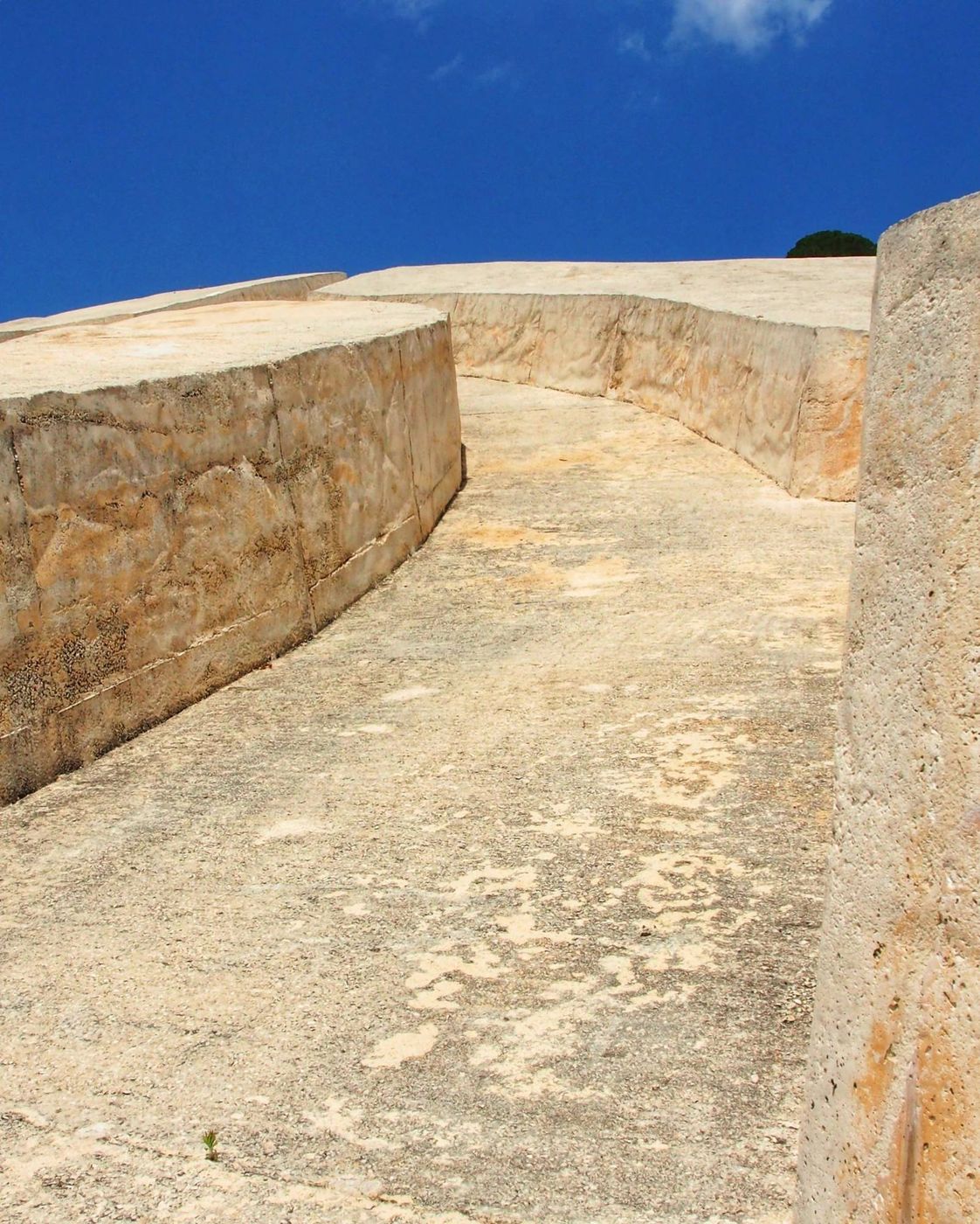 Il Cretto di Burri: muri curvi di cemento chiaro che salgono verso un cielo blu intenso